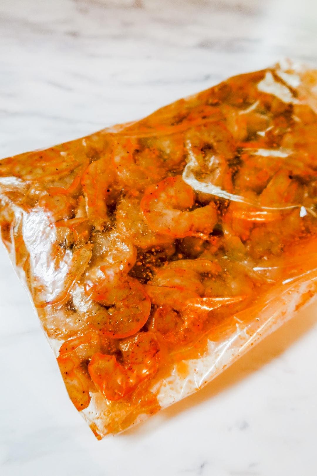 Raw shrimp marinating in a homemade taco seasoning blend